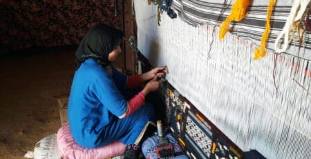 Berber Weaver on the weaving machine making moroccan rugs