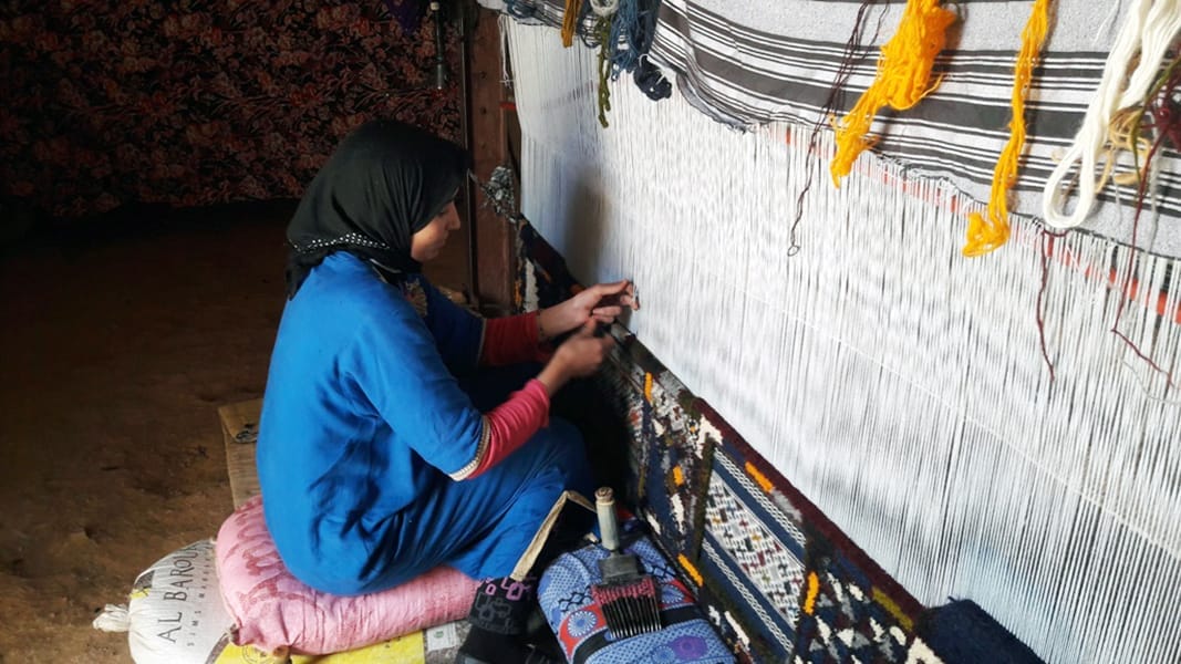 Berber Weaver on the weaving machine making moroccan rugs